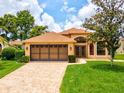 Inviting home with a tile roof, lush lawn, and a paver driveway leading to a two-car garage at 11350 Copley Ct, Spring Hill, FL 34609
