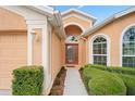 Inviting home entrance with arched doorway, decorative windows, and manicured bushes at 12071 Wexford Blvd, Spring Hill, FL 34609