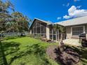 Well-manicured backyard featuring a screened-in lanai, lush green grass, and a charming white picket fence at 13627 Glaze Brook Dr, Hudson, FL 34667