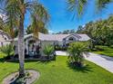 Beautiful single-Gathering home featuring a lush green yard, mature palms, and a curved driveway at 13627 Glaze Brook Dr, Hudson, FL 34667