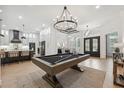 Open-concept space featuring a pool table and modern chandelier with access to a kitchen and dining area at 15413 Azra Dr, Odessa, FL 33556