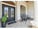 Inviting front porch with tiled flooring, seating, and a decorative front door at 15413 Azra Dr, Odessa, FL 33556