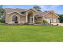 Beautiful home featuring a manicured lawn, arched windows, and a two-car garage at 18244 Autumn Lake Boulevard, Hudson, FL 34667