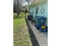 Home exterior featuring air conditioning unit, trash bins, and fenced yard access at 2158 Clayton Ave, Spring Hill, FL 34609