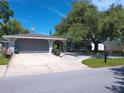 Charming single-story home featuring a well-maintained lawn, mature trees, and a curved driveway leading to a two-car garage at 3207 Jarvis St, Holiday, FL 34690