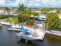 Waterfront home with private dock featuring boat lift, patio with lounge seating, and tropical landscaping at 4917 Marlin Dr, New Port Richey, FL 34652