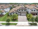 Aerial view of a two-story home with a tile roof, a three-car garage, and a beautifully landscaped yard at 5001 Night Star Trl, Odessa, FL 33556