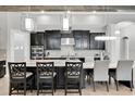 Modern kitchen with black cabinetry, stainless steel appliances, pendant lighting, and a large center island with seating at 5001 Night Star Trl, Odessa, FL 33556
