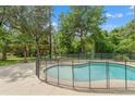 Backyard featuring a refreshing in-ground pool with a safety fence, surrounded by lush greenery at 5487 Valley View Dr, Brooksville, FL 34601