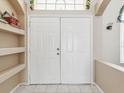 Bright entryway with double doors, decorative window, shelving, and neutral color palette at 6028 Dorset Rd, Spring Hill, FL 34608