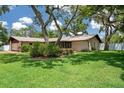 Landscaped home exterior showcasing mature trees, lush lawn, and screened porch, creating a serene and inviting outdoor space at 7630 Landmark Dr, Spring Hill, FL 34606