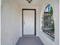 Close-up of a white front door with black trim, surrounded by textured walls at 9005 Lido Ln, Port Richey, FL 34668