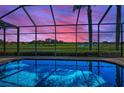 Relaxing screened-in pool overlooking a lush golf course and pond at 9933 Milano Dr, Trinity, FL 34655