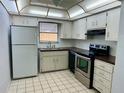 Efficient kitchen with stainless steel oven, white cabinets, and tiled flooring at 10014 Kingswood Ln, Port Richey, FL 34668