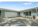 View of the single-story home showing the 2-car garage, front door, and landscaped entry at 1004 Peninsula Ave, Tarpon Springs, FL 34689