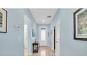 Bright hallway with light blue walls, tile flooring, and multiple doorways at 11308 Mollymawk Ct, New Port Richey, FL 34654