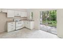 Well-lit kitchen with white appliances and cabinets, granite countertops, and sliding doors leading to the patio at 11751 Key Lime Dr, New Port Richey, FL 34654