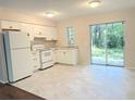 Bright kitchen features white cabinetry, appliances, and tile flooring with sliding glass doors to the outdoors at 11751 Key Lime Dr, New Port Richey, FL 34654