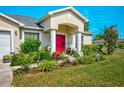 Close-up of a home's front entrance, highlighting the vibrant garden and red front door at 13317 Pinellas Ave, Spring Hill, FL 34609