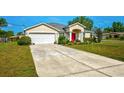 Beautiful home with a well-kept lawn, a long driveway, and a vibrant red front door at 13317 Pinellas Ave, Spring Hill, FL 34609