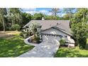 An aerial view of the garage shows manicured landscaping and a driveway, surrounded by lush greenery on a sunny day at 13460 Pia Ct, Spring Hill, FL 34609