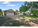 View of the home from the street, showcasing a large driveway and mature trees surrounding the property at 2866 Thistle N Ct, Palm Harbor, FL 34684