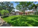 Home's front elevation with well-maintained lawn and landscaping, showcasing its curb appeal at 2866 Thistle N Ct, Palm Harbor, FL 34684