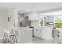 Modern white kitchen featuring an island with bar seating and stainless steel appliances at 3907 Headsail Dr, New Port Richey, FL 34652