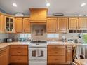 Kitchen featuring wooden cabinets, tile backsplash, and a white electric range at 4292 Tahiti Dr, Hernando Beach, FL 34607