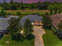 Beautiful aerial view of a gray home with a spacious driveway backing onto a lush golf course at 4485 Gevalia Dr, Brooksville, FL 34604