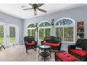 Bright sunroom with large arched windows, comfortable wicker furniture, and serene wooded views at 4960 Hidden Knob Trl, Spring Hill, FL 34609