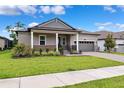 Charming single-story home featuring a manicured lawn, gray stucco, and a two-car garage at 5005 Southern Valley Loop, Brooksville, FL 34601