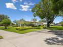 A landscaped yard surrounds this ranch-style home with flowering shrubs and a mature shade tree at 6823 Oak Hill Dr, New Port Richey, FL 34653