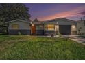 Charming single-story home featuring neutral colors, an attached garage, and a beautifully landscaped front yard at sunset at 6989 300 Th N Ave, Clearwater, FL 33761