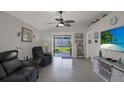 Open living room with high ceiling, ceiling fan, sliding glass doors, tile floor, and television at 7736 Chadwick Dr, New Port Richey, FL 34654