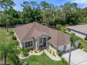 Aerial view of a beautifully landscaped single-story home with a brown roof and well-manicured lawn in a quiet community at 9019 Flagstick Ln, Hudson, FL 34667