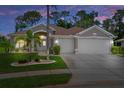 Inviting home exterior with a well-manicured lawn and attached two-car garage at dusk at 9019 Flagstick Ln, Hudson, FL 34667