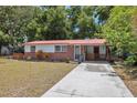 Attractive single-story home with a red metal roof, well-manicured lawn, and a convenient long driveway at 9306 21St, Tampa, FL 33612
