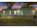 Charming light blue home with a garage door and inviting front entrance at twilight at 9744 Rainelle Ln, Port Richey, FL 34668