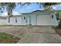 Charming light blue home featuring a garage and a quaint arched doorway at 9744 Rainelle Ln, Port Richey, FL 34668