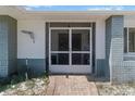 Close up of the front entrance with a screen door and brick walkway leading to the home at 10267 Elgin Blvd, Spring Hill, FL 34608