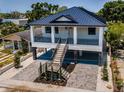 Two-story home showcasing its metal roof, double staircases, and ground floor parking, nestled among lush trees at 111 E Cedar St, Tarpon Springs, FL 34689
