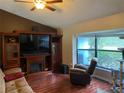 Comfortable living room with fireplace, large windows, and hardwood floors at 12090 Stoneville Ct, Spring Hill, FL 34609
