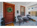 Cozy front porch with seating area, brick details, and a welcoming dark red front door at 124 Athens St, Tarpon Springs, FL 34689