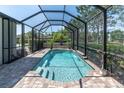 Inviting screened-in pool area with clear water and brick pavers, surrounded by lush landscaping at 12420 Rangeland Blvd, Odessa, FL 33556