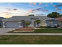 Charming single-story home at dusk, featuring manicured landscaping, a two-car garage, and inviting curb appeal at 1245 Overland Dr, Spring Hill, FL 34608