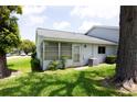 Exterior view with green grass, mature tree and view of screened porch at 12511 Dearborn Dr, Hudson, FL 34667
