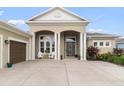 Inviting home exterior featuring an elegant entrance with columns and a well-maintained lawn at 16697 Courtyard Loop, Land O Lakes, FL 34638