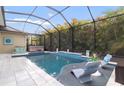 Screened-in pool with luxurious lounge chairs and hot tub surrounded by lush landscaping at 16697 Courtyard Loop, Land O Lakes, FL 34638