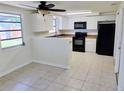 Well-lit kitchen featuring white cabinets, black appliances, and tile floors at 2051 Peggy Dr, Holiday, FL 34690